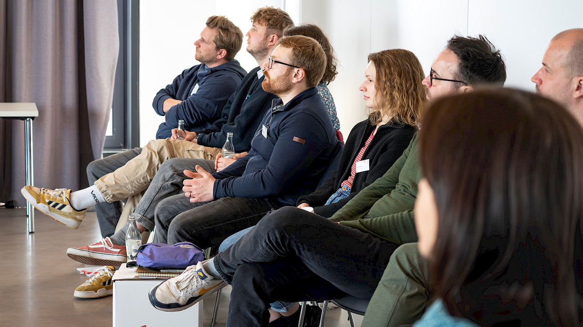 Menschen sitzen in einem Seminarraum und hören aufmerksam einem Vortrag zu.