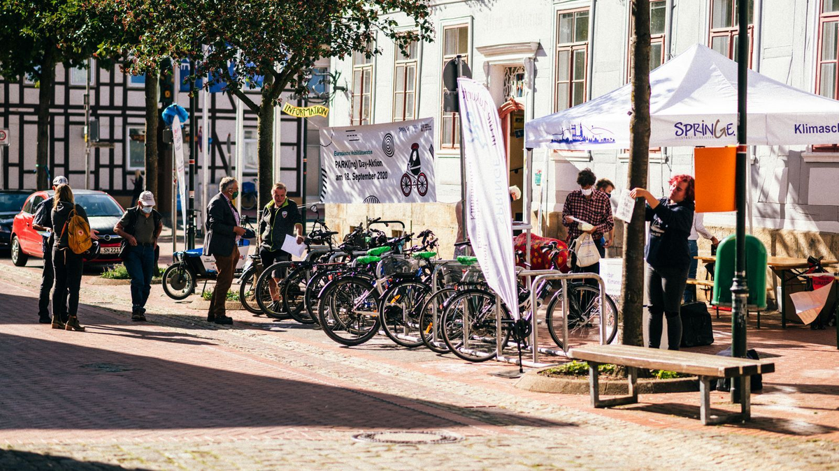 Aktionstag mit Fahrrädern, Infoständen und Pavillon „SPRINGE – Klimaschutz“ auf einer sonnigen Straße vor historischen Gebäuden.