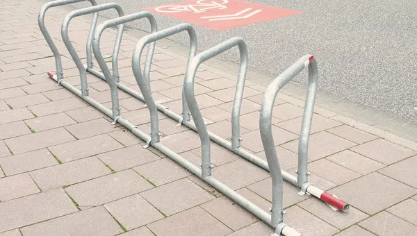 Ein mobiler Fahrradständer aus verzinktem Stahl steht am Gehwegrand neben einem Radfahrstreifen.