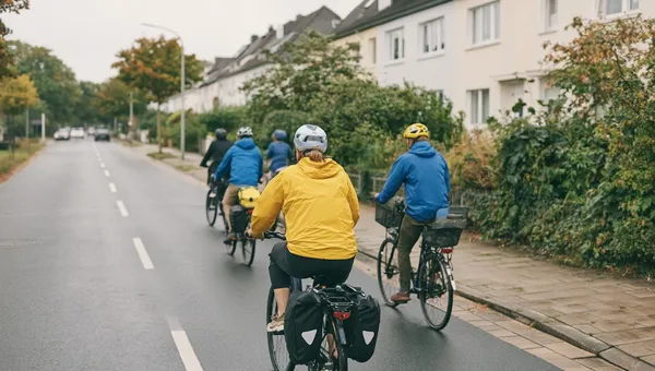 Eine Gruppe Radfahrender fährt, von hinten gesehen, eine Wohnstraße entlang.