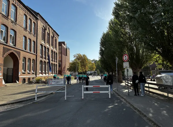 Gesperrte Straße zwischen den Schulgebäuden am Schulzentrum in Lehrte: Absperrbaken und ein Schild „Schulgelände“, dahinter gehen Schüler*innen über die Fahrbahn.