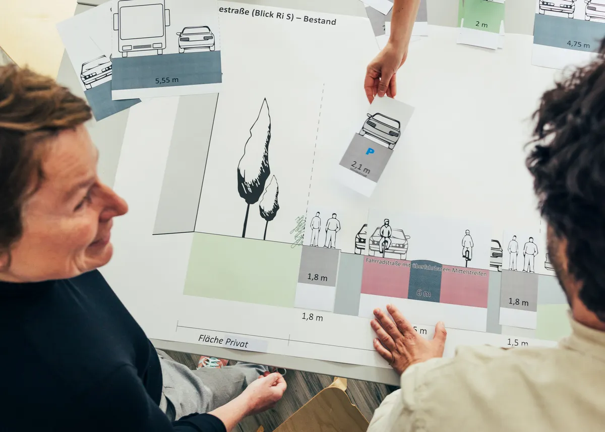 Eine Frau steht im Profil vor einer Wand mit Plänen und Diagrammen.