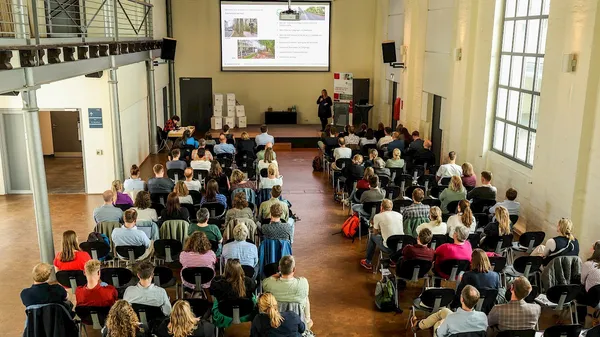 Publikum im Werkhof Hannover bei einem Vortrag der MOBILOTSIN – Blick von hinten auf Sitzreihen und Bühne mit Präsentation
